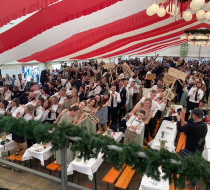 Feiernder Patenverein stehend auf Bierbänken mit Partyschildern in der Hand