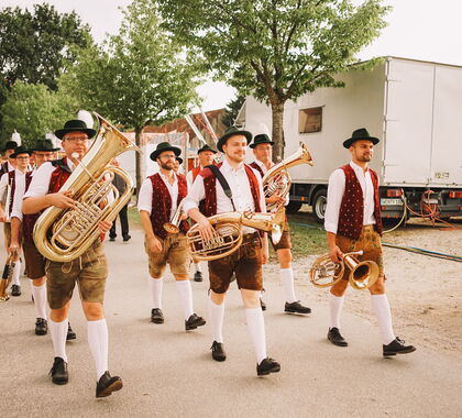 Musiker der Bayernkapelle beim Einzug in ein Festzelt gefolgt vom Jubelverein