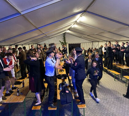 Feierndes Publikum steht auf Bierbänken in einem Festzelt